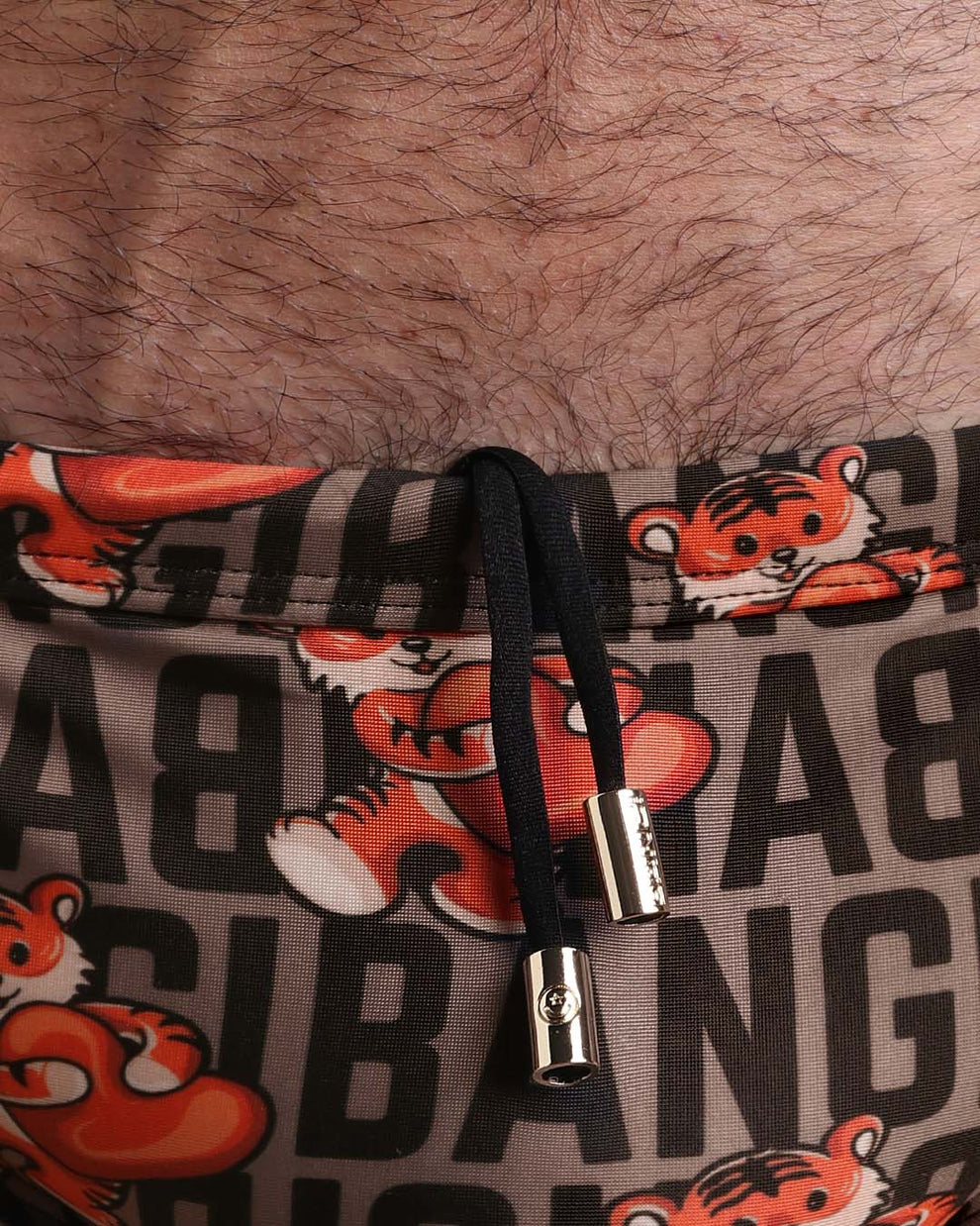 Close-up view of the TIGER HEARTS men’s drawstring briefs showing black cord with custom branded golden cord ends, and matching custom eyelet trims in gold.