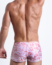 Back view of a model wearing TOILE DE MIAMI (RED) men’s swim shorts in white with red artwork made by the Bang! Miami official brand of men's swimwear.