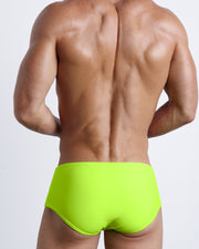 Back view of a male model wearing men’s swim sungas in a neon highlighter yellow color by the Bang! Clothes brand of men's beachwear.