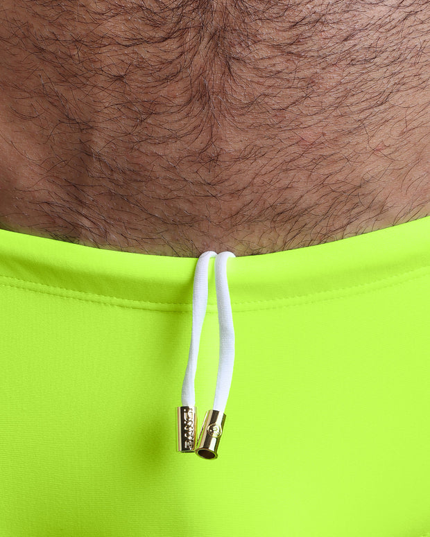 Close-up view of the ULTRA NEON Swim Sunga mens swimsuit a bright neon green color with white internal drawstring cord showing custom branded golden buttons by BANG! clothing brand.