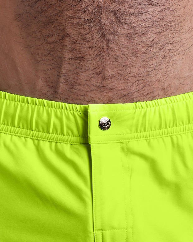 Close-up view of the men’s summer mini shorts, showing custom branded metal button in gold.