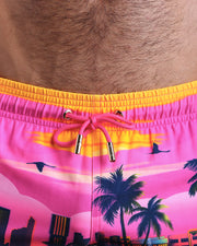 Close-up view of the UNDER THE NEON SKY men’s summer shorts, showing bright pink cord with custom branded golden cord ends, and matching custom eyelet trims in gold.