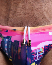 Close-up view of the UNDER A NEON SKY men’s summer shorts by BANG! clothing brand, showing white cord with custom branded golden cord ends, and matching custom eyelet trims in gold.