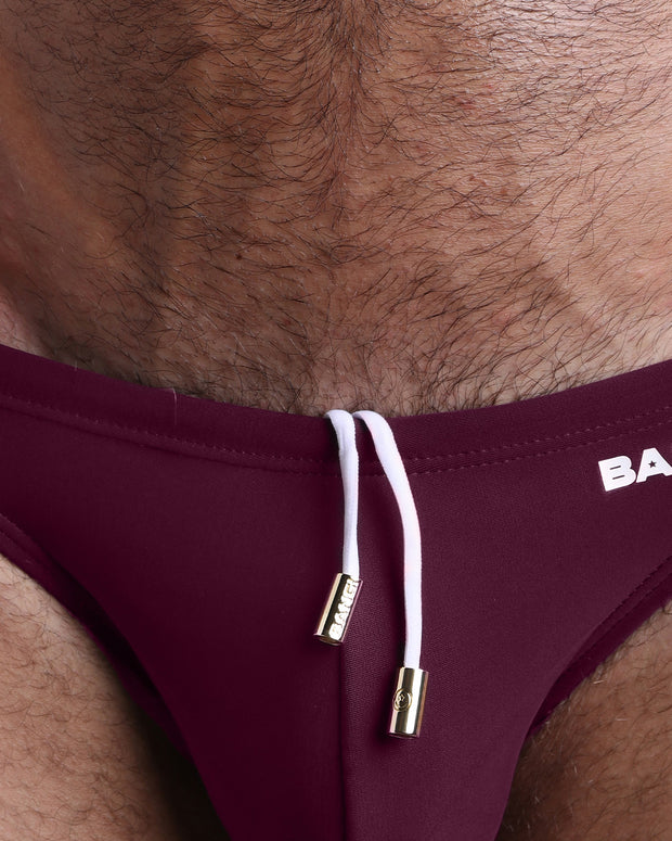 Close-up view of the VERY BERRY men’s drawstring briefs showing white cord with custom branded golden cord ends, and matching custom eyelet trims in gold.