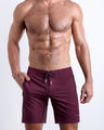 Frontal view of sexy model wearing the VERY BERRY men’s all-purpose swimwear bottoms in a burgundy red color by the Bang! brand of men's beachwear from Miami.