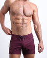 Male model wearing the VERY BERRY men’s flex shorts in burgundy red color by the Bang! brand of men's beachwear from Miami.