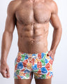 Front view of model wearing the VIA POSTAL men’s beach shorts in white with colorful Miami pop art postage stamps by the Bang! Clothes brand of men's beachwear from Miami.