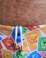 Close-up view of the VIA POSTAL Swim Sunga mens swimsuit with colorful postal stamps graphics with white internal drawstring cord showing custom branded golden buttons by BANG! clothing brand.
