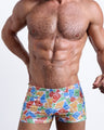 Frontal view of a sexy male model wearing men's swimsuit with mini pockets in VIA POSTAL in a colorful Miami pop art postage stamps designed by the Bang! Menswear brand from Miami.