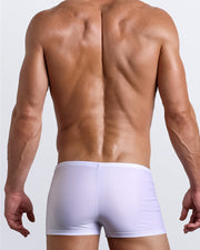 Back view of a male model wearing men’s swim trunks in white color by the Bang! Clothes brand of men's beachwear from Miami.