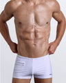 Frontal view of a sexy male model wearing men’s swimsuit with mini pockets in white color by the Bang! Menswear brand from Miami.