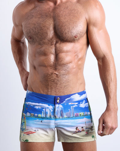 Front view of model wearing the WISH YOU WERE HERE men’swim bottoms featuring Miami Beach skyline art by the Bang! Clothes brand of men's beachwear from Miami.