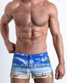 Frontal view of model wearing the WISH YOU WERE HERE men’s square leg swim trunks featuring Miami Beach skyline art by the Bang! brand of men's beachwear from Miami.