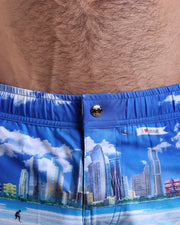 Close-up view of the WISH YOU WERE HERE men’s beach shorts, showing custom branded metal button in gold by Bang!