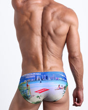 Back view of male model wearing the WISH YOU WERE HERE beach briefs for men by BANG! Miami featuring a colorful Miami inspired artwork.