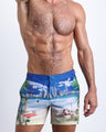 Front view of model wearing the WISH YOU WERE HERE men’s beach tailored shorts in a sky blue color featuring the Miami Beach skyline by the Bang! Clothes brand of men's beachwear from Miami.