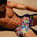 front view of a sexy male model wearing BANG Miami yeah yeah show shorts unique prints in a beach setting summer body ripped