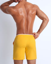 Back view of the men's above-knees length fitness workout shorts in a solid dark yellow color by BANG! menswear Miami.