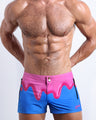 Front view of model wearing the YOU MELT ME men’swim bottoms in a bright blue color featuring pink melting ice cream print by the Bang! Clothes brand of men's beachwear from Miami.