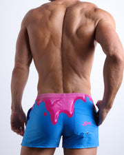 Back view of male model wearing the YOU MELT ME beach trunks in men in blue and hot pink melting ice cream theme for men by BANG! Miami.