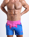 Front view of model wearing the YOU MELT ME men’s beach tailored shorts in a bright blue color featuring pink melting ice cream print near the waist  by the Bang! Clothes brand of men's beachwear from Miami.