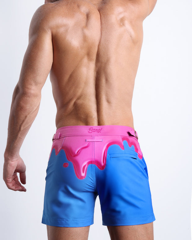 Back view of male model wearing the YOU MELT ME beach trunks for men by BANG! Miami in blue and hot pink melting ice cream theme.